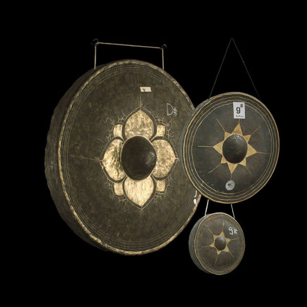 Three gongs of varying sizes against a black background, showcasing intricate golden patterns and bosses, used as musical percussion instruments