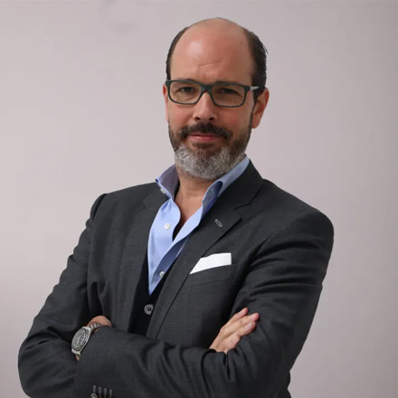 Portrait of Herbert Tucmandl, CEO and Founder, a man with a beard and glasses, wearing a suit, arms crossed.