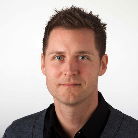 Headshot of Martin Saleteg, Head of Software Development, smiling slightly with short dark spiked hair, wearing a black shirt and grey cardigan.
