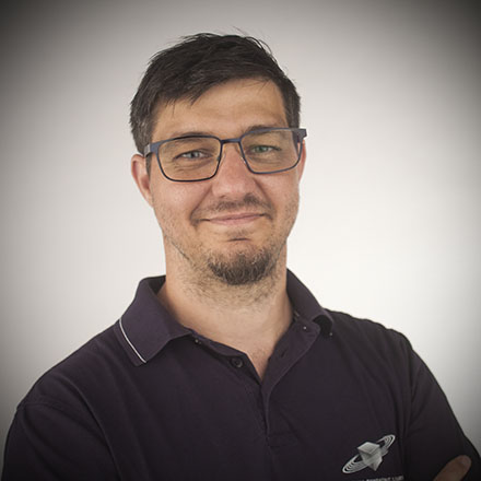 Headshot of Bernd Mazagg, Chief Recording and Mixing Engineer, smiling and wearing glasses and a dark polo shirt with a logo.