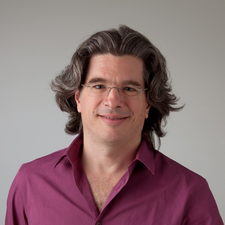 Martin Tichy, Head of Marketing, smiling with shoulder-length gray hair and glasses, wearing a purple shirt.