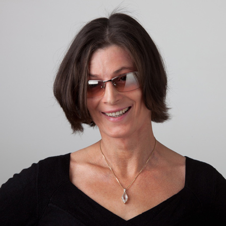 Sabine Tucmandl, Head of Synchron Stage, smiles wearing sunglasses and a necklace.