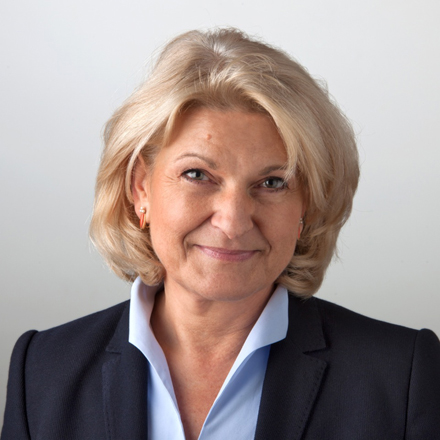 Headshot of Ingrid E. Dubowy, the Commercial Director, smiling. She has blonde hair and is wearing a dark suit jacket over a light blue collared shirt.