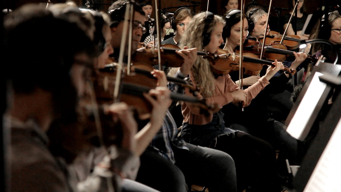 Musicians of the Big Bang Orchestra with headphones playing violins in a recording studio for Vienna Symphonic Library Synchron Instruments.