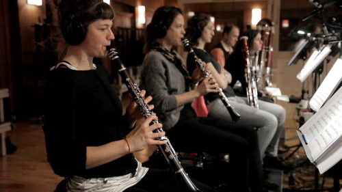 Big Bang Orchestra recording session with musicians playing clarinets and other wind instruments, sheet music on stands, acoustic room, Vienna Symphonic Library