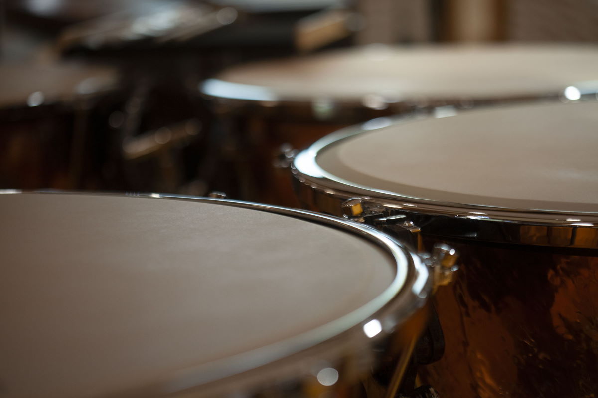 Close-up view of multiple snare drums, part of the Vienna Symphonic Library's Synchron Percussion II instrument series, showing muted drumheads and shining chrome rims against dark wooden bodies.