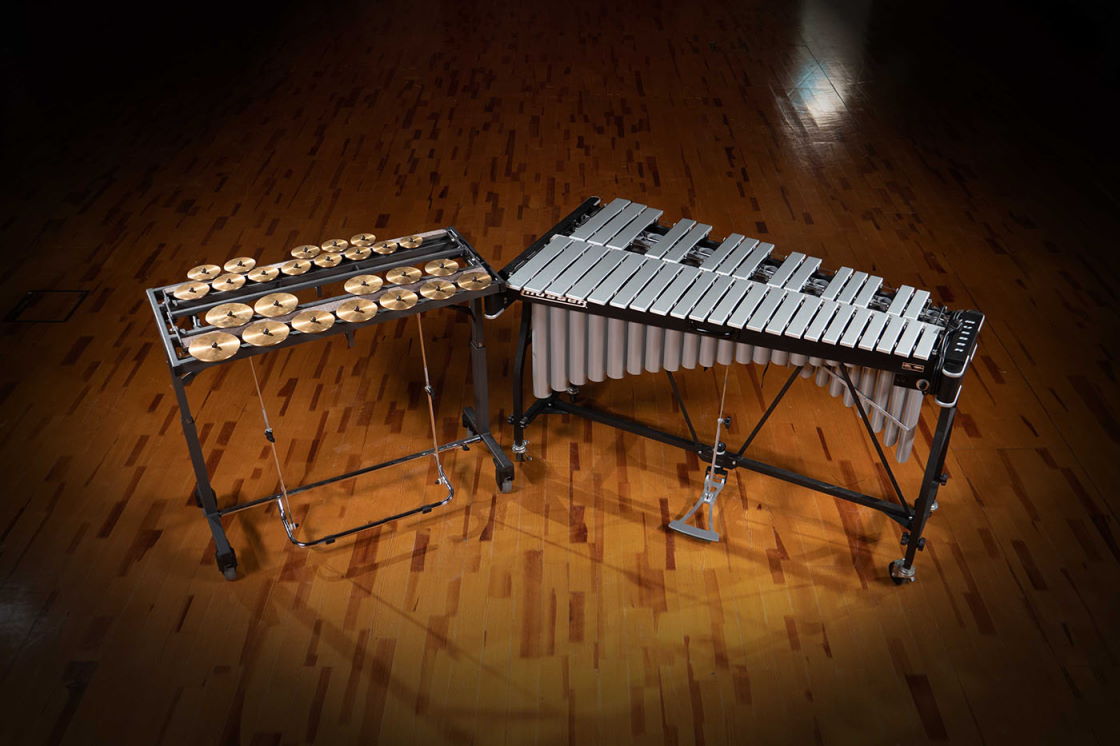Synchron Percussion II instruments: a glockenspiel with shining metal bars and a cymbal array, on a wooden floor.