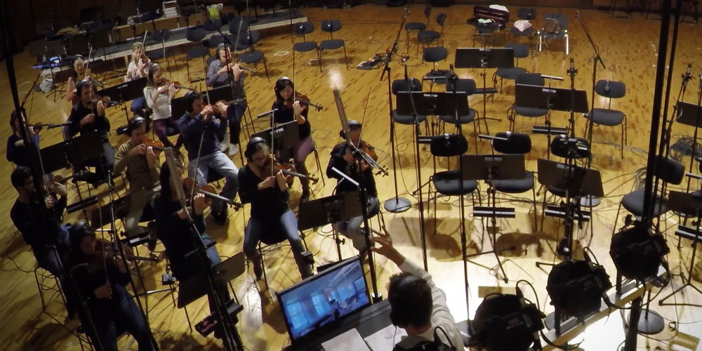 Orchestra musicians playing violins in a recording studio with microphones for Vienna Symphonic Library Synchron Strings I.