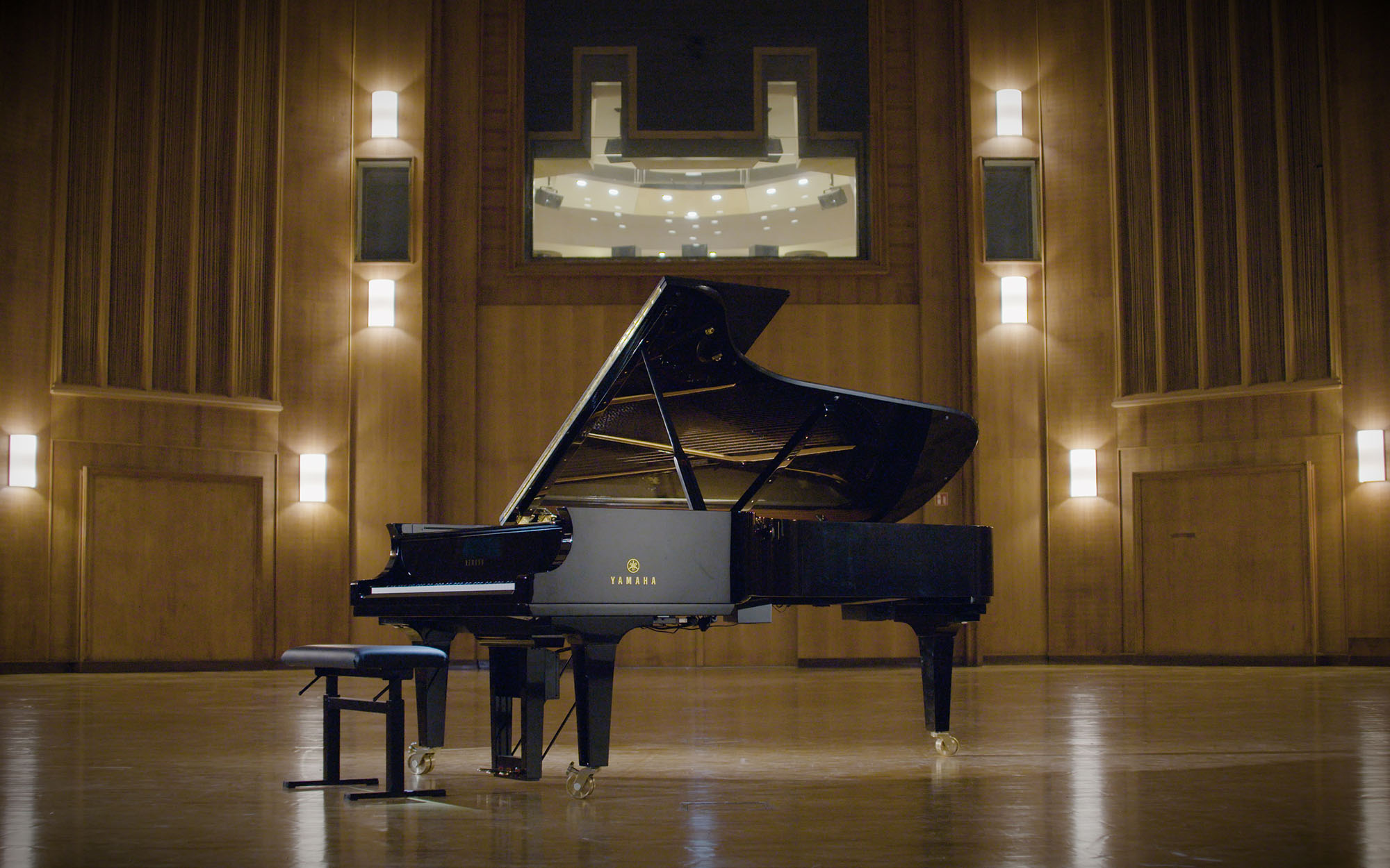 Yamaha CFX concert grand piano on a stage in a performance hall with a piano bench, representing a high-end music instrument