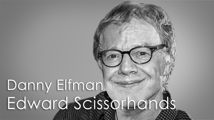 Black and white portrait of Danny Elfman, the composer of Edward Scissorhands, wearing glasses and smiling.