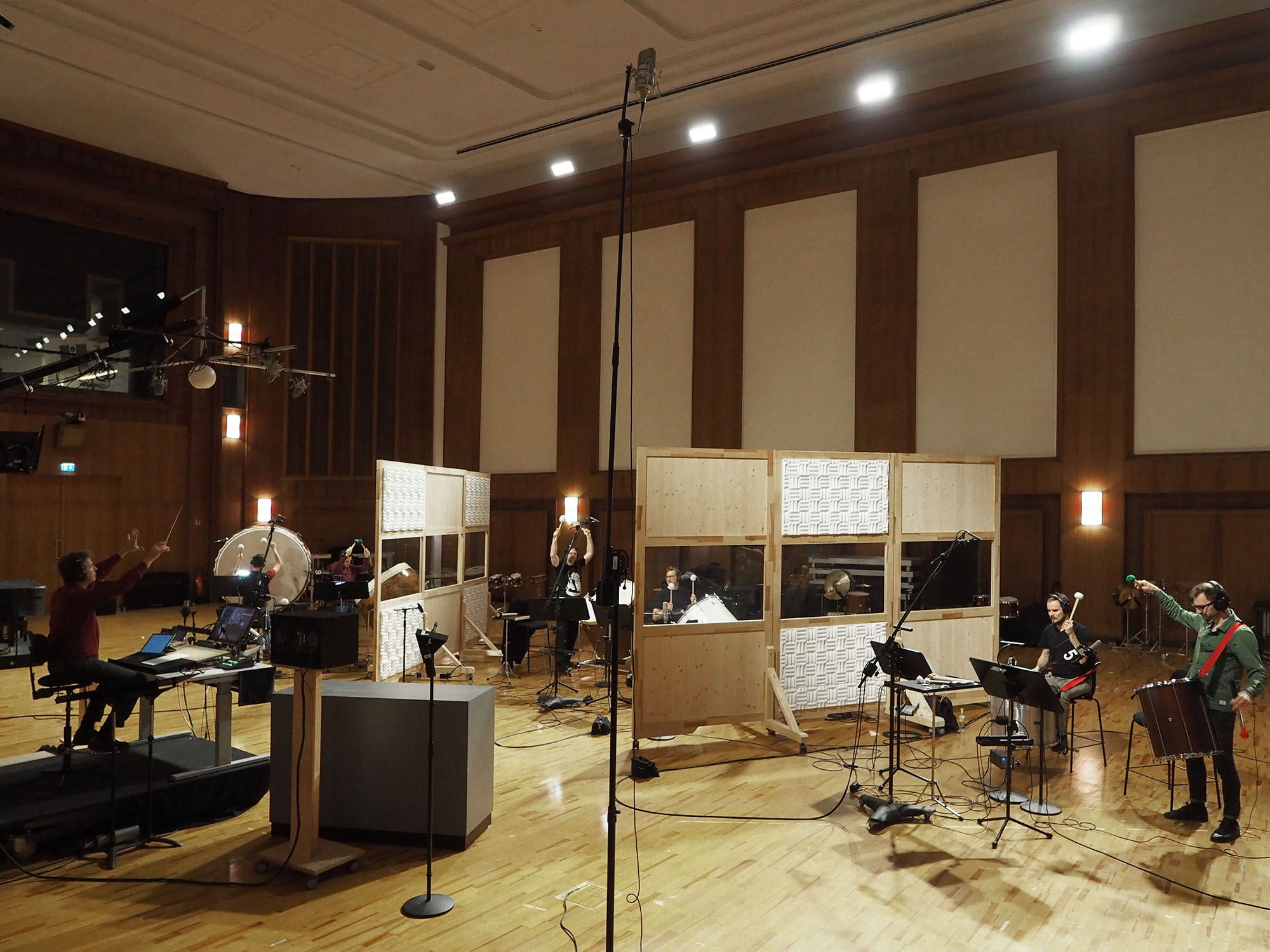 A modern recording studio with musicians surrounded by instruments, microphones, and sound baffles, capturing a dynamic performance.