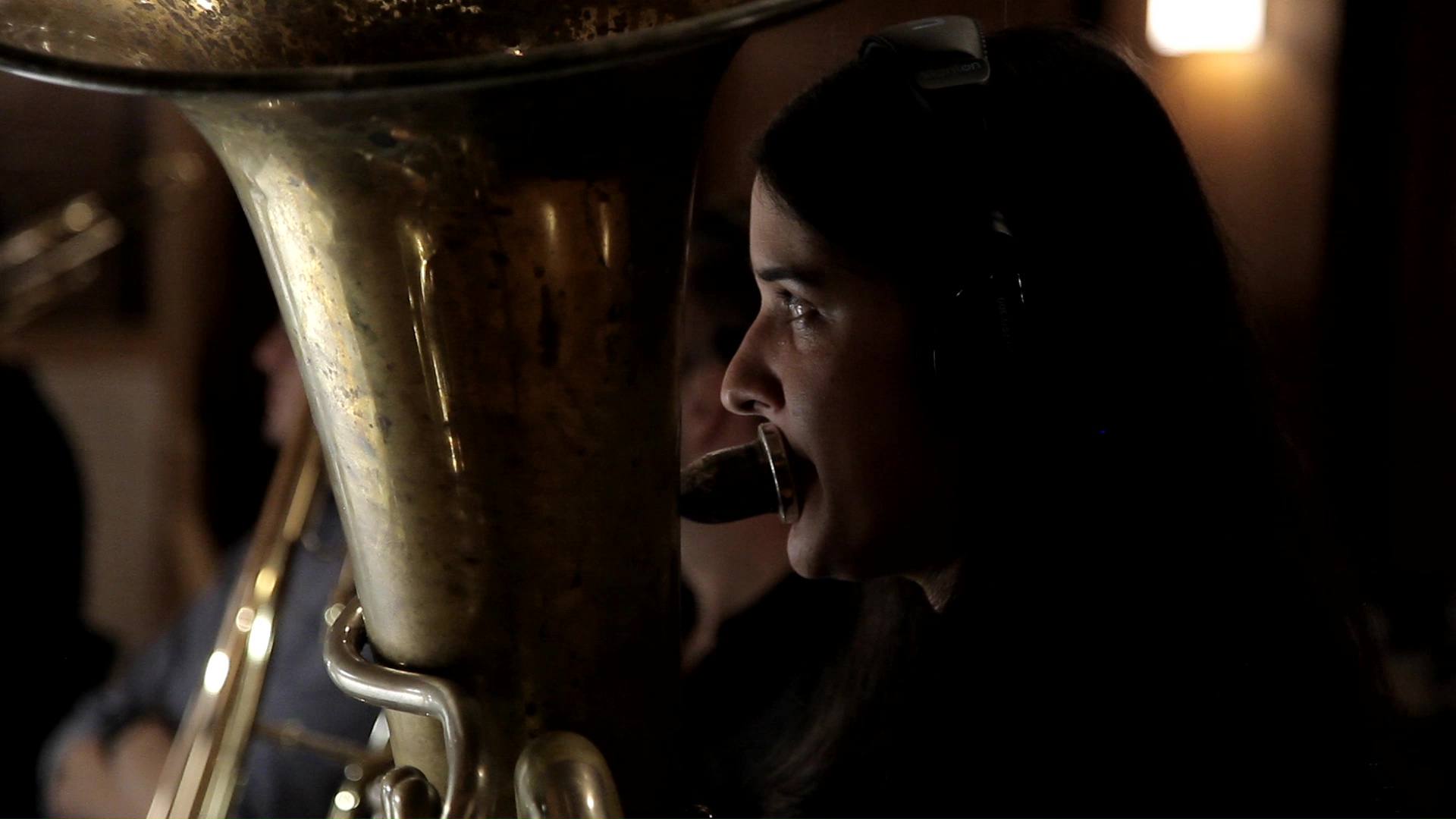 Musician playing a tuba, studio recording, close up, dark setting