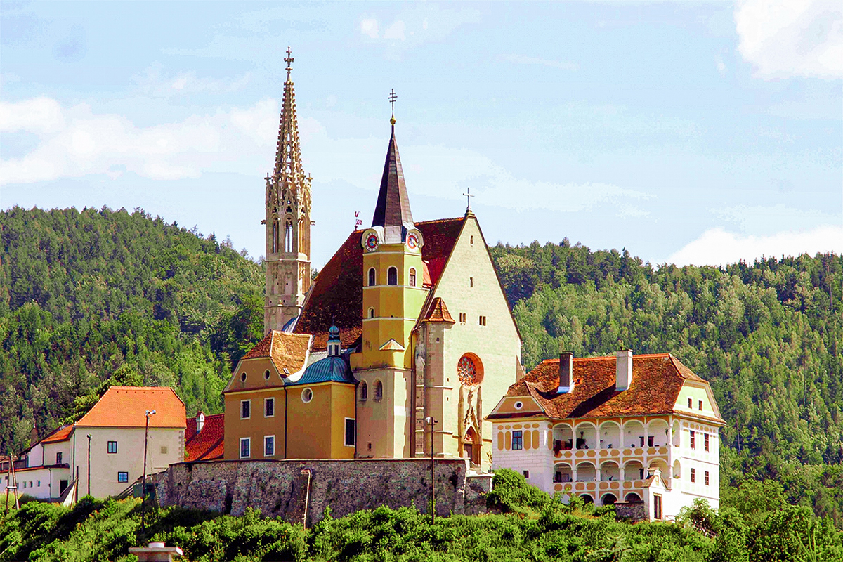 Gothic Spire, Church building, and historic houses on hillside surrounded by green forest.