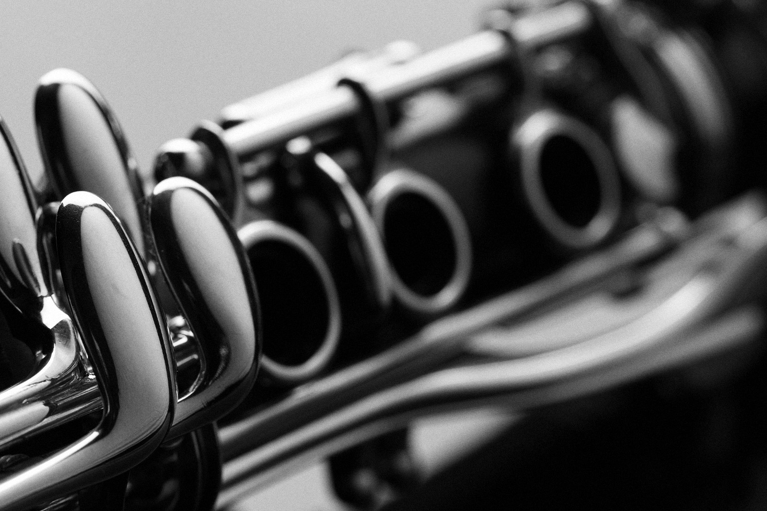 Monochrome close-up of a clarinet's silver keys and tone holes, showcasing its intricate musical instrument details.