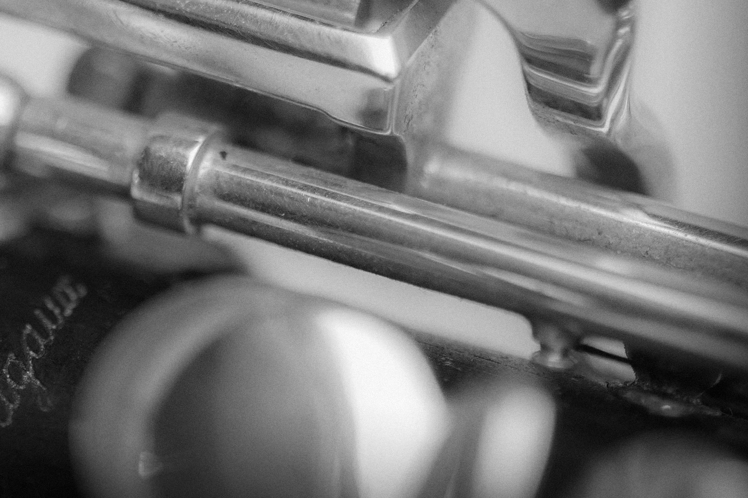 Monochrome close-up of a musical instrument's metallic and wooden components, showcasing intricate mechanisms and textures.