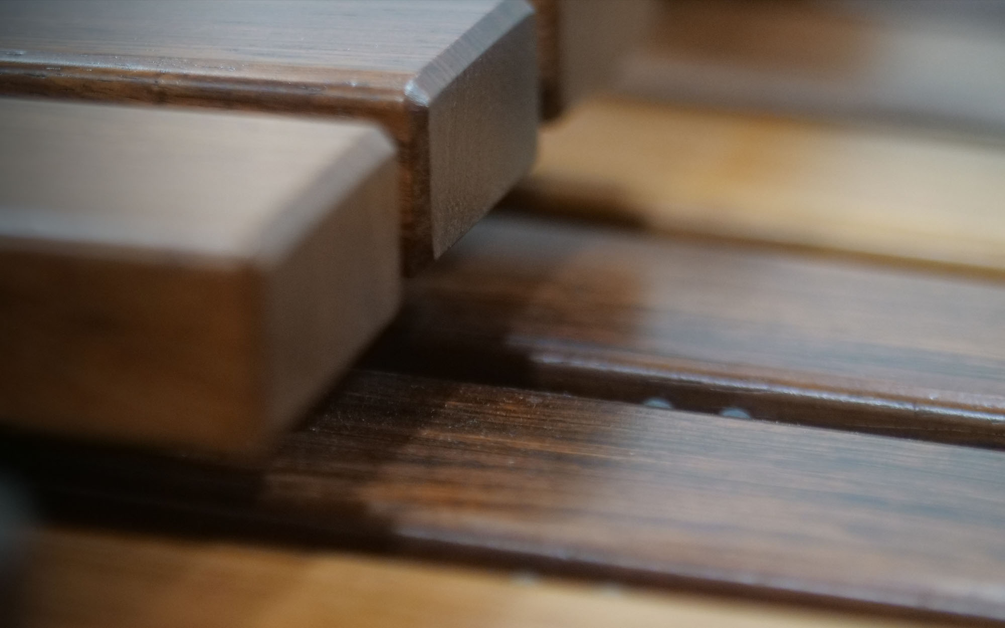 Close-up of wooden blinds or slats, showing rich brown tones and textured grain with subtle light reflections.