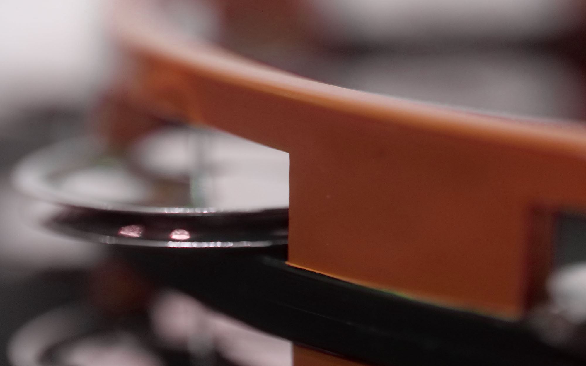 Close-up of a blurred record player's orange tone arm and spinning vinyl record.