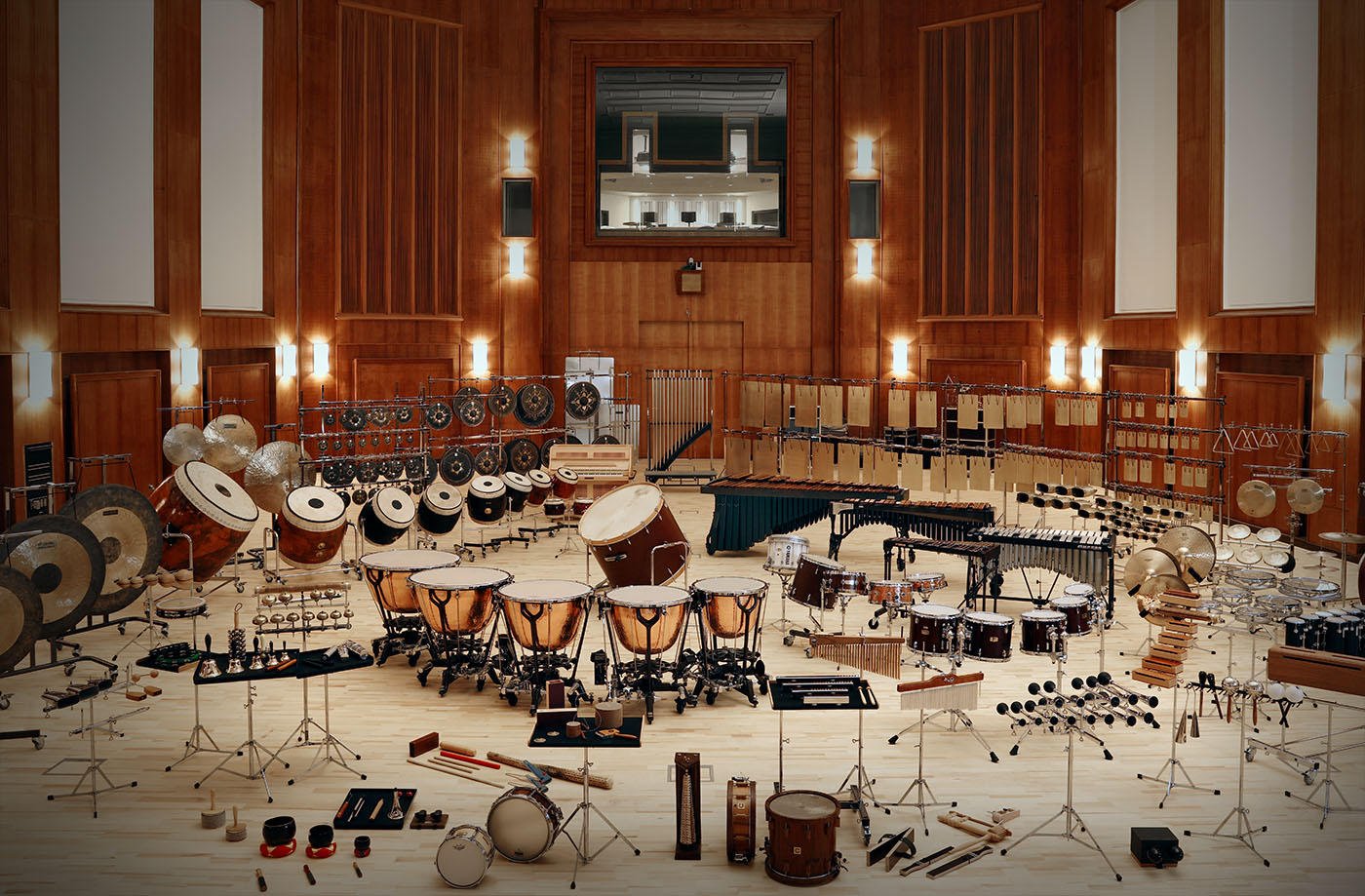 Orchestral percussion instruments including timpani, bass drums, gongs, chimes, and mallet instruments arranged on a wooden stage in the Vienna Synchron Stage.