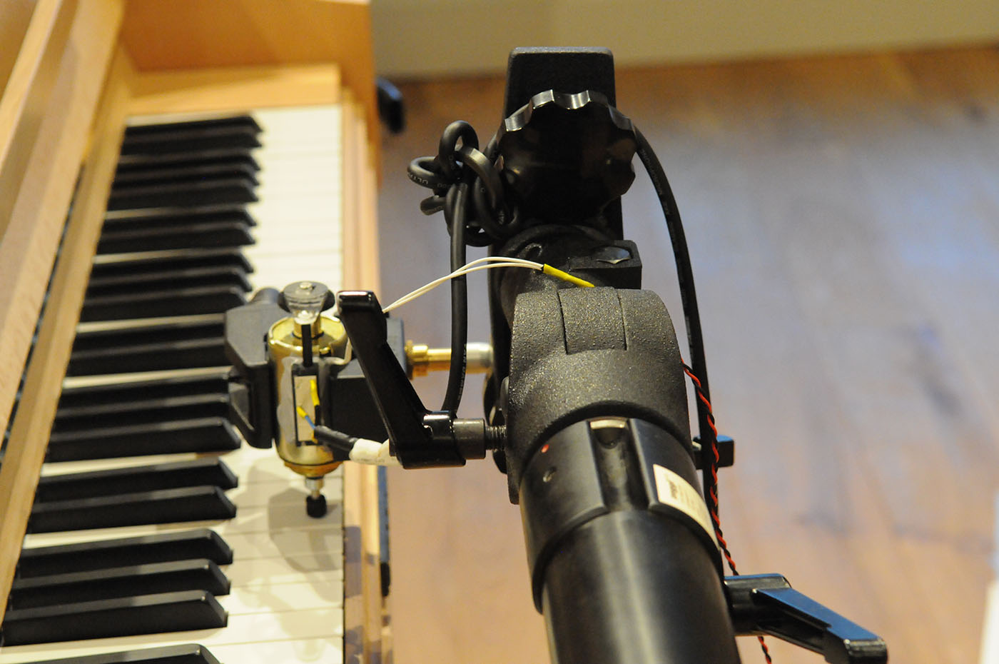 Close-up of a robot playing a piano keyboard, showing robotic mechanisms, wires, and parts of the black and white piano keys.