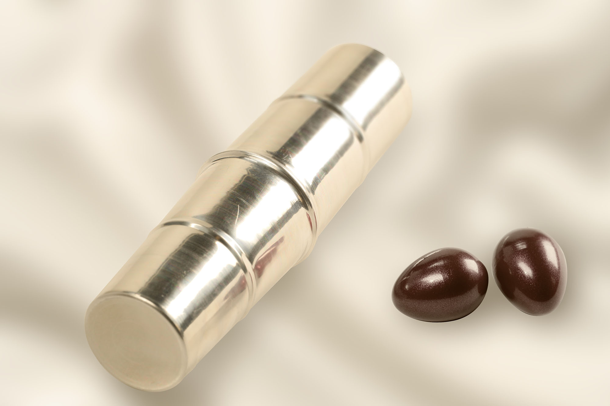 Shiny silver cylindrical object alongside two dark brown egg-shaped items.