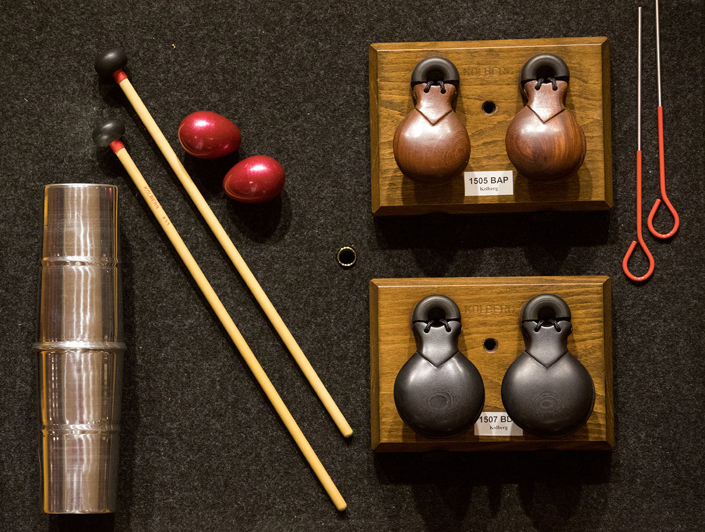 Assortment of Kolberg percussion instruments including castanets, mallets, shakers, and cymbal sleeves.