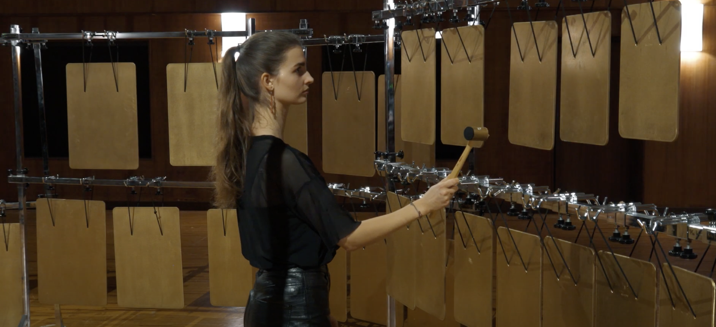 Young woman playing plate bells with a mallet, showcasing the musical instrument's low C2-B4 range.