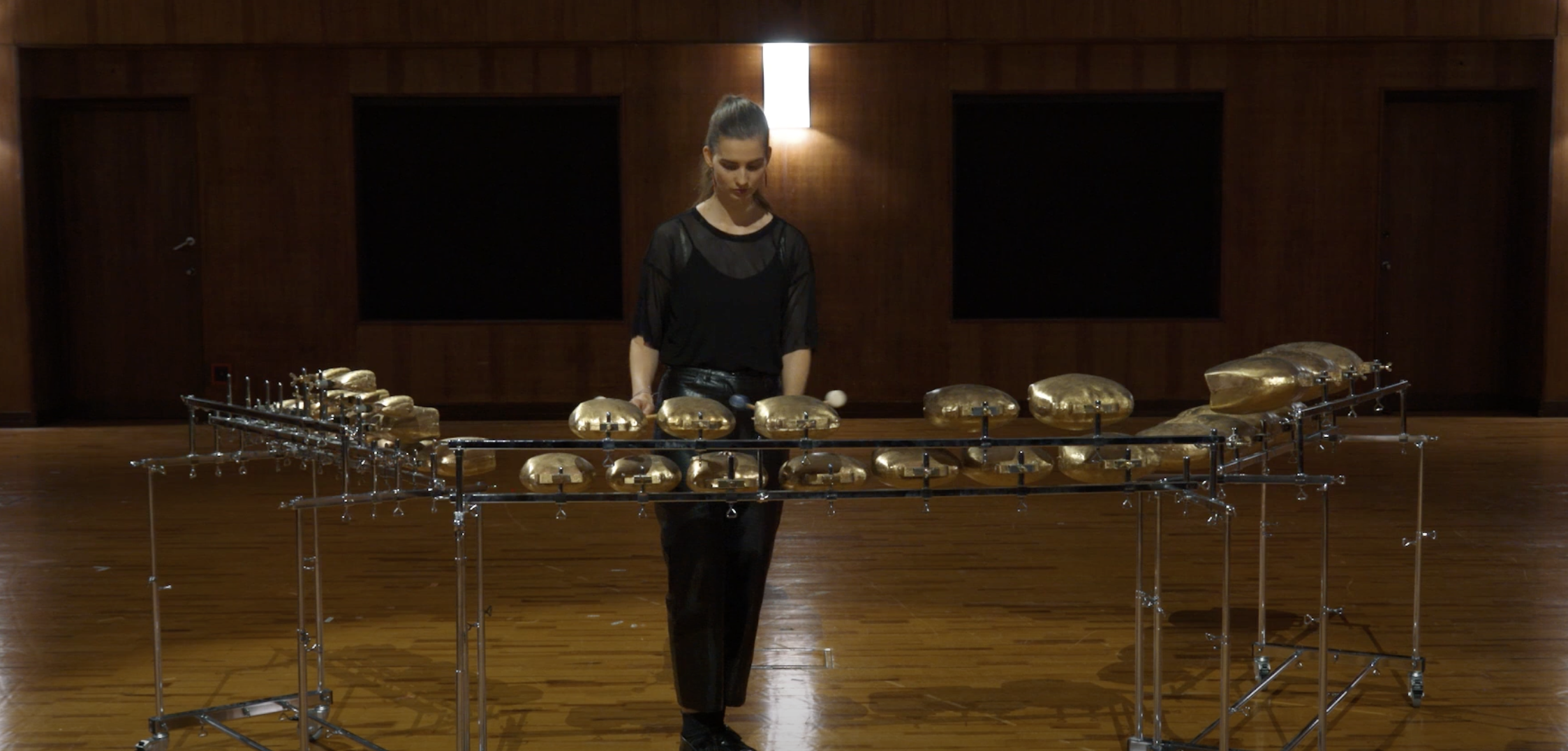 Musician playing Cencerros Almglocken, a melodic percussion instrument with a large set of gold bells arranged on a metal frame.
