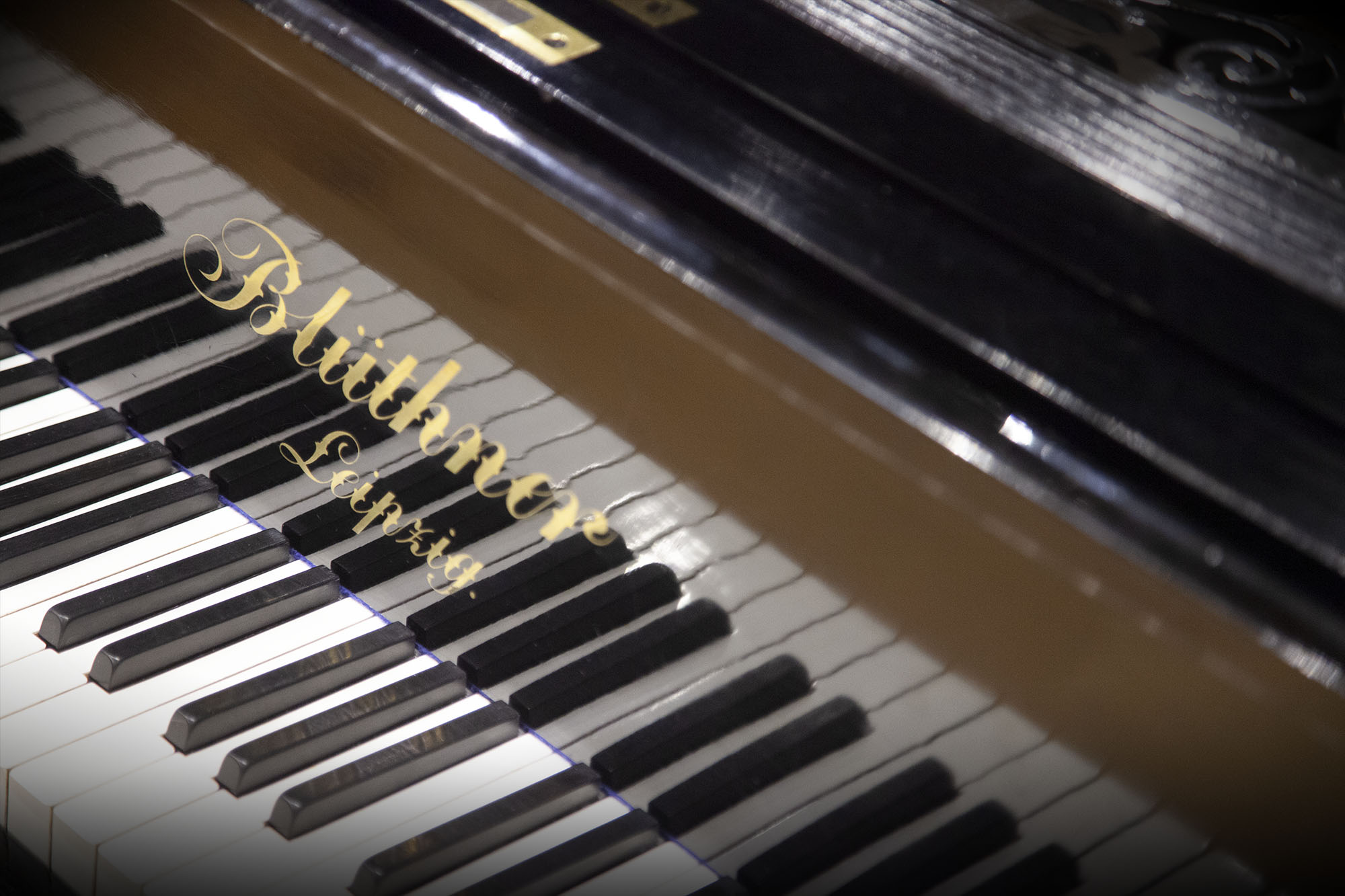 Close-up view of a Blüthner Leipzig grand piano keyboard with black and white keys and the gold Blüthner Leipzig logo.
