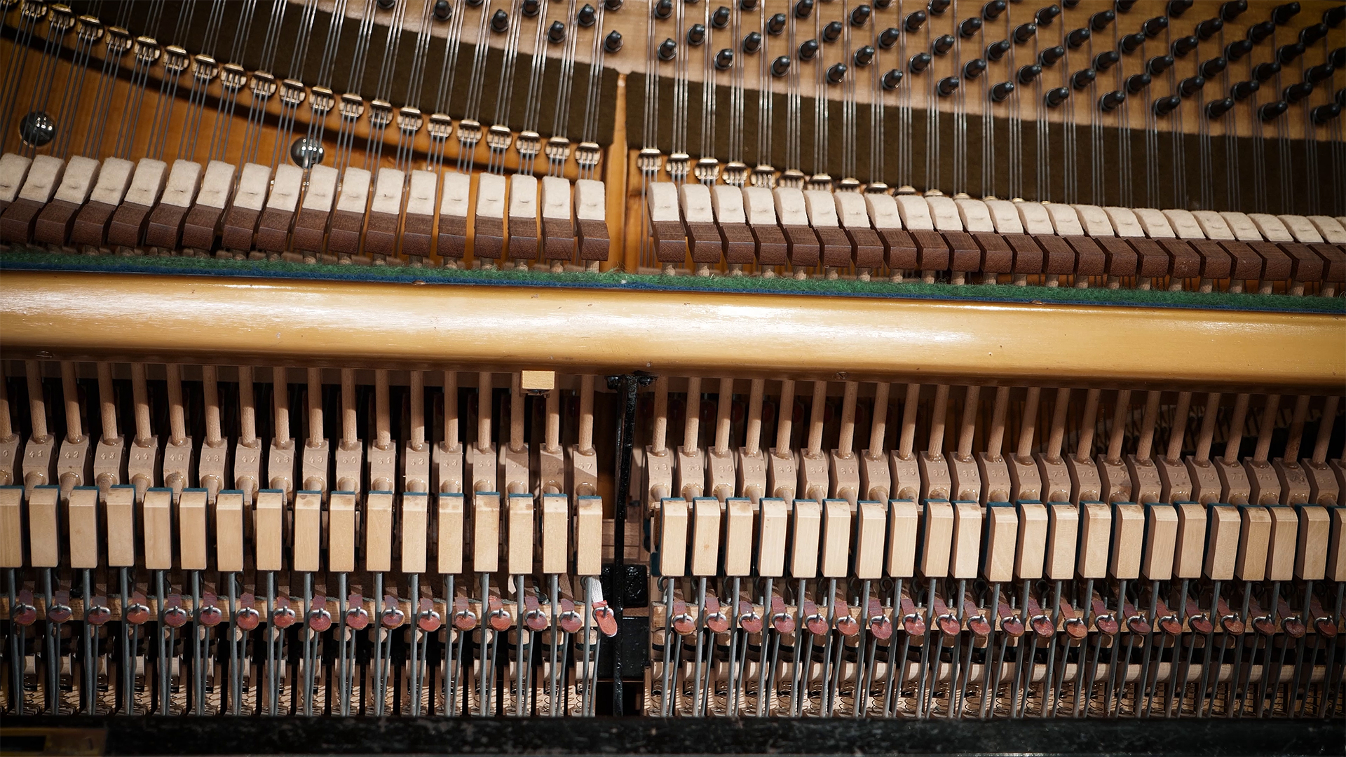 Internal view of a piano's intricate mechanism, showcasing hammers, strings, and dampers.