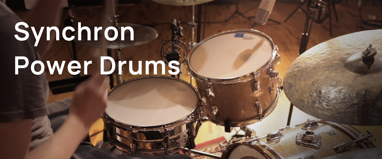 Musician playing a drum set for Synchron Power Drums, showcasing the snare, tom, and cymbal.