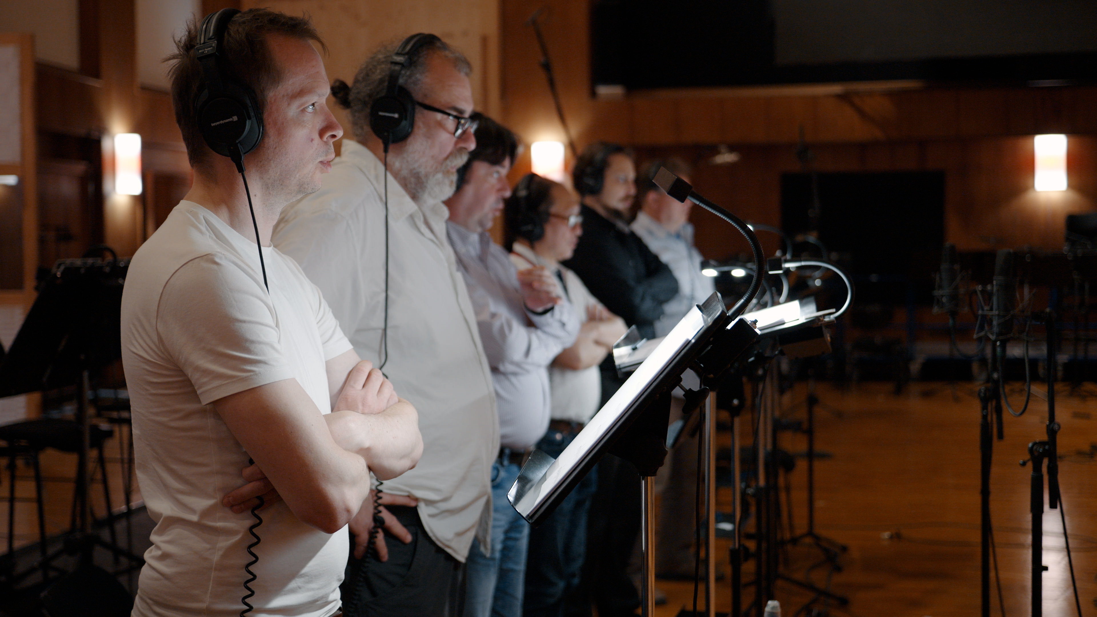 Music producers and sound engineers in a recording studio, wearing headphones and observing a recording session.