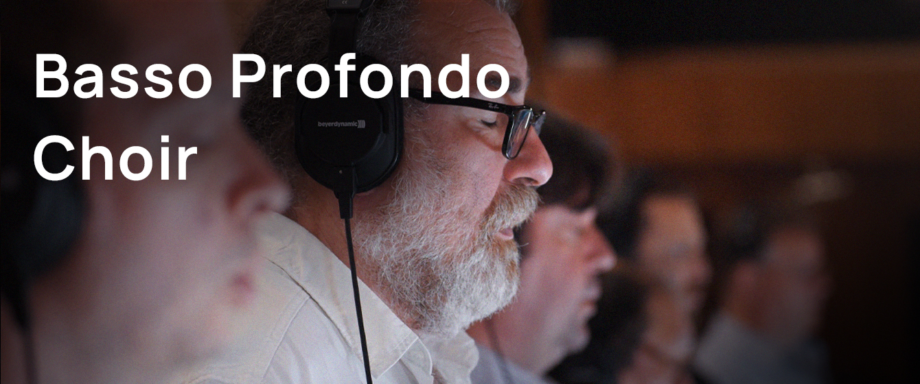 A man with a white beard and black eyeglasses wears headphones and sings in a choir. The text Basso Profondo Choir is overlaid on the left.