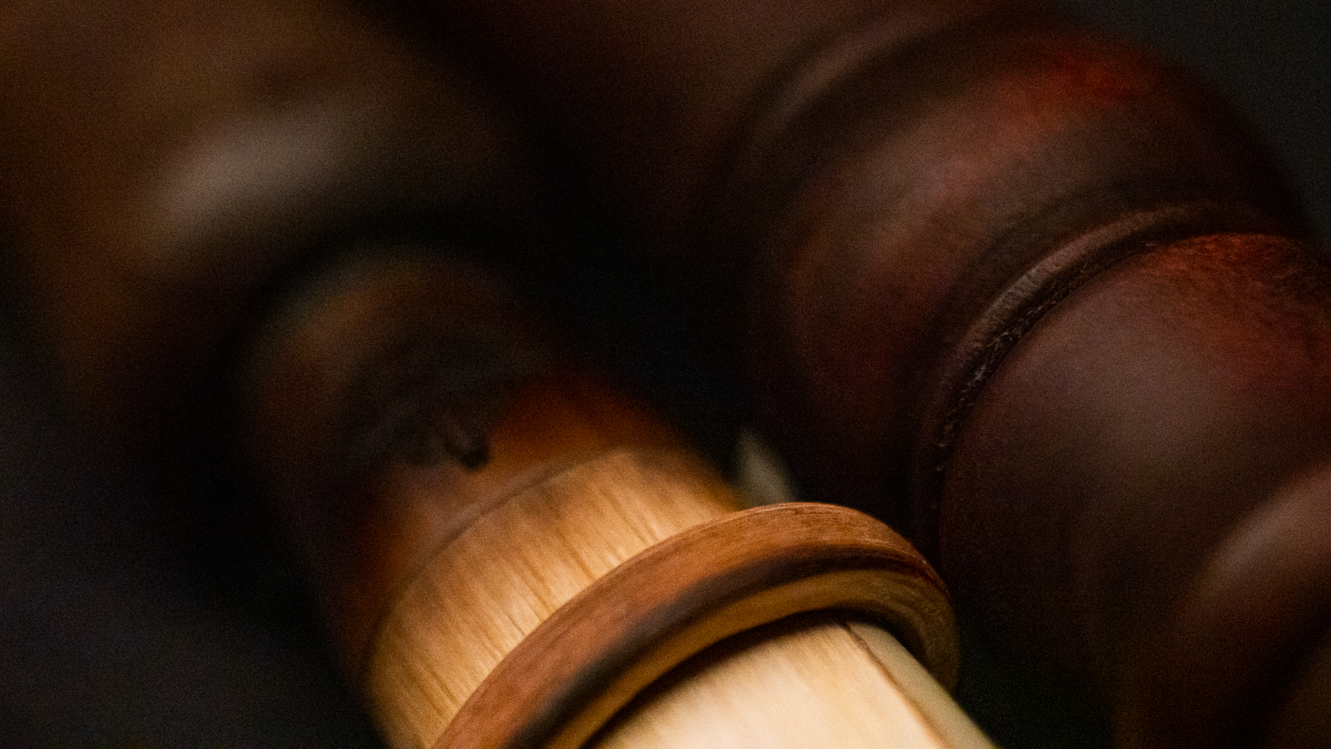 Close-up of a dark wooden gavel or mallet handle with visible light and dark woodgrains, showcasing craftsmanship and details.