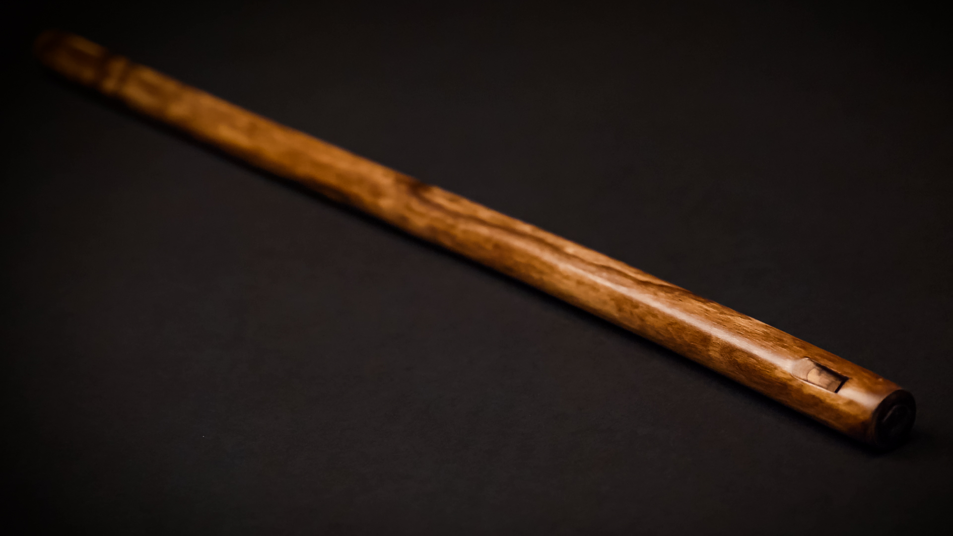 Handcrafted wooden flute with warm brown tones on a dark background.